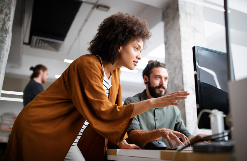 two-professional-it-workers-at-a-desk-discussing